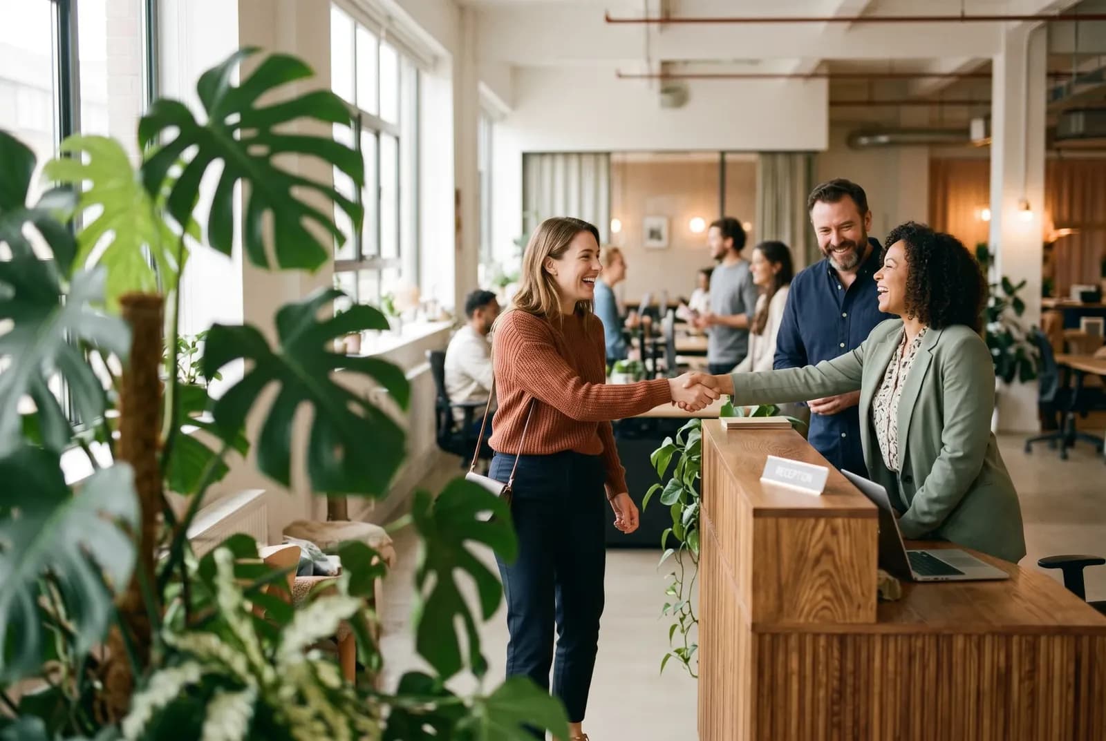 Nieuwe medewerker wordt verwelkomd bij de receptie van een licht kantoor
