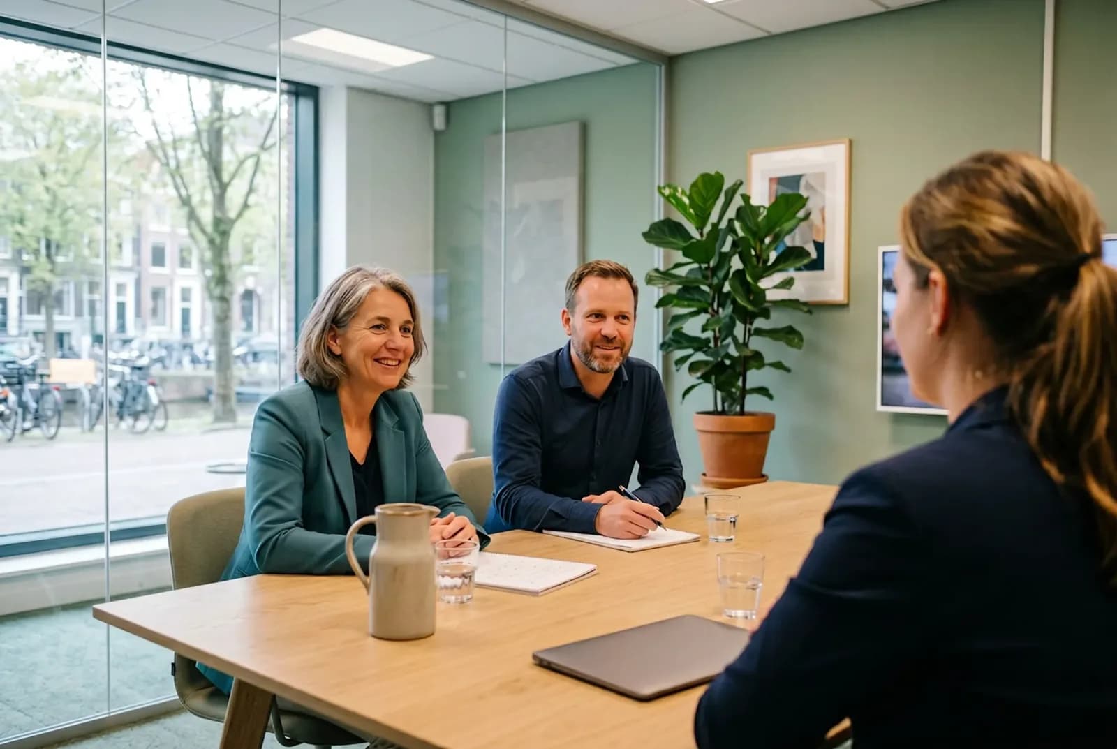 Sollicitatiegesprek aan een lichte houten tafel in een gemeentekantoor